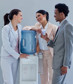 Business people speaking next to a water cooler in office